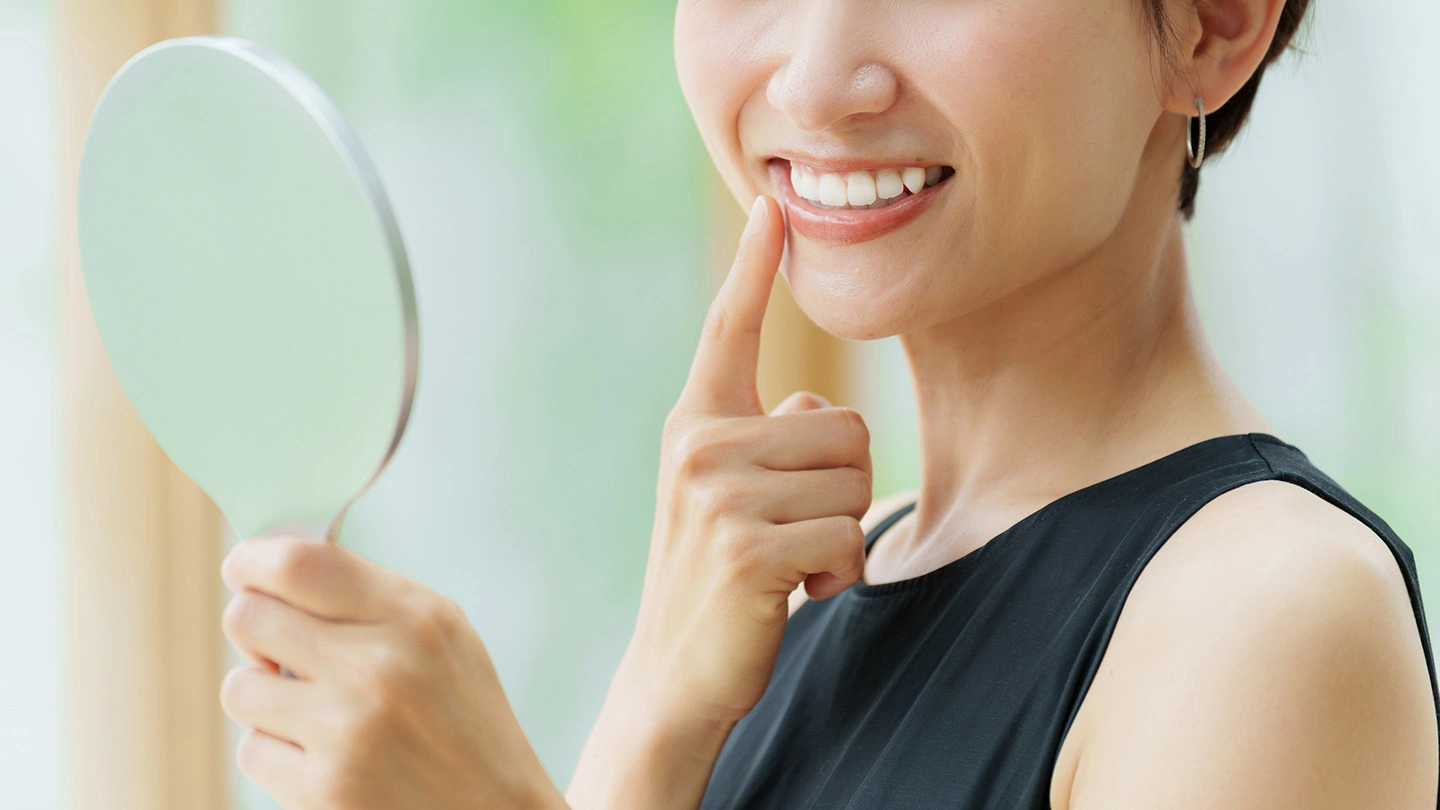 鏡で歯のチェックをする女性